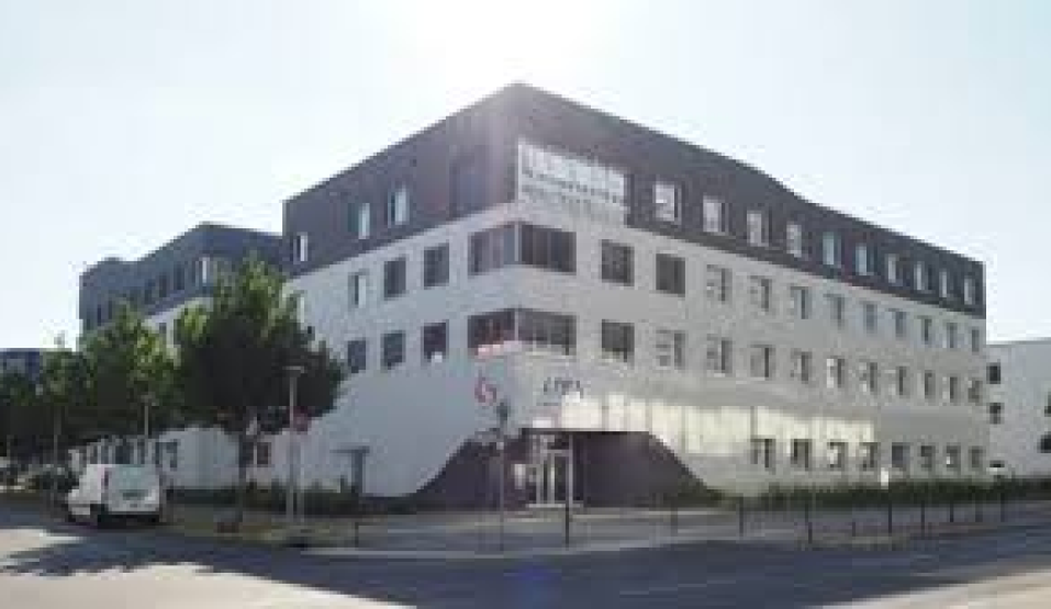 Firmengebäude von LTB Lasertechnik Berlin mit modernem Design und Logo an der Fassade unter blauem Himmel.